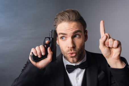 excited-businessman-showing-idea-gesture-while-holding-weapon-